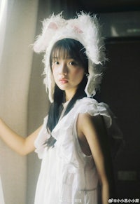 a girl in a white dress wearing a bunny hat